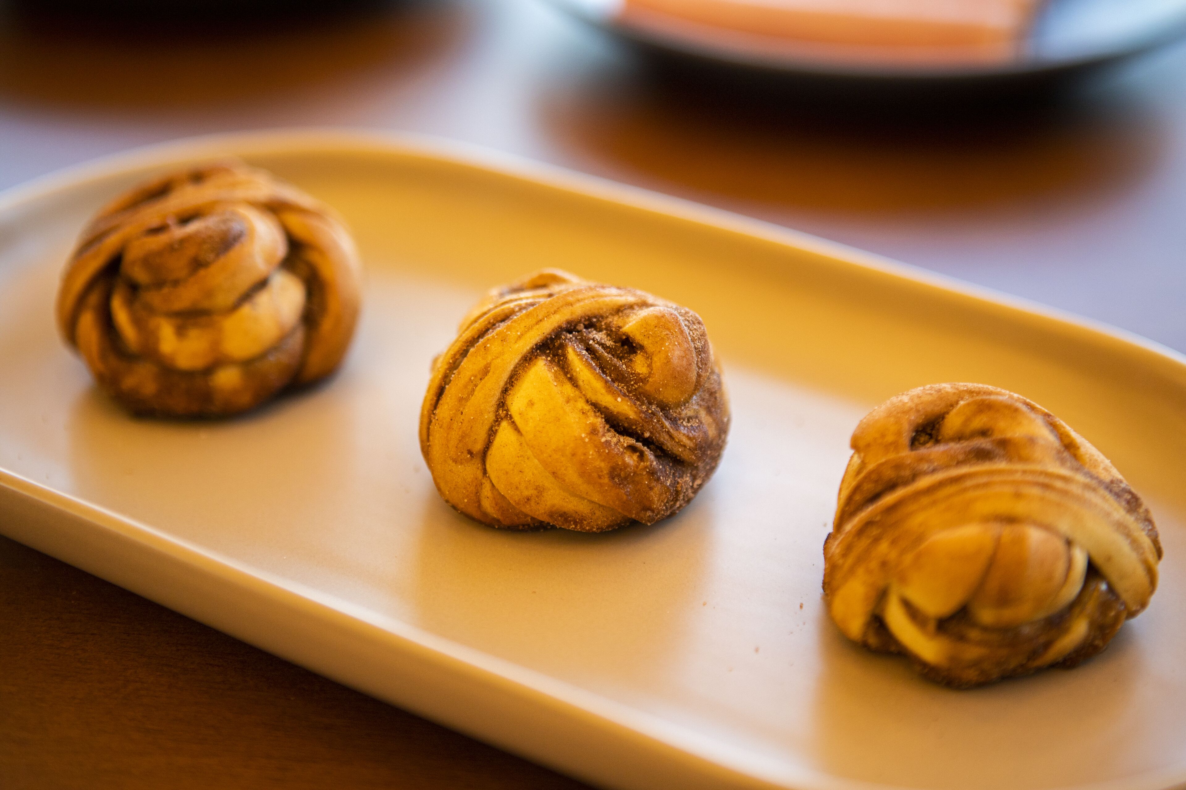 Three cinnamon rolls on a rectangular plate.