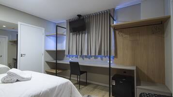 Een hotelkamer met een bed, een bureau, een stoel, een televisie en een garderobe.