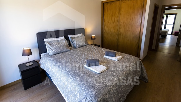Ein Schlafzimmer mit einem großen Bett, zwei Nachttischen, einem Holzschrank und einem Spiegel.