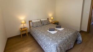 Ein Schlafzimmer mit einem Bett, zwei Nachttischlampen, einem Nachttisch und Holzboden.