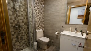 Ein modernes Badezimmer mit Duschkabine aus Glas, Toilette und Waschbecken mit Spiegel darüber.