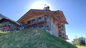 Eine Holzhütte mit Steinunterbau, Balkonen und blauem Himmel.