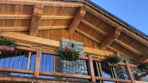Ein Holzhaus mit Balkon, Steinmauern und Blumenkästen.