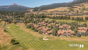 Et resort med flere bygninger, en golfbane og bjerge i baggrunden.