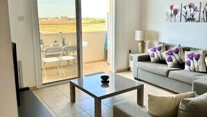 Una sala de estar con un sofá, una mesita de centro y vistas a un espacio exterior con sillas.