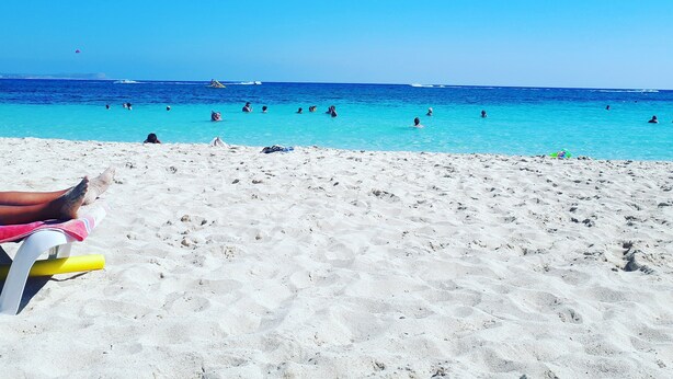 Una playa con agua azul cristalina y una orilla arenosa.