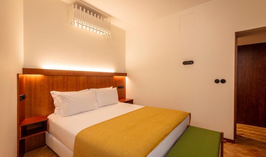 A neatly arranged hotel room with a large bed, bedside tables, a bedside lamp, and a door.