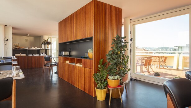 Et moderne opholdsrum med en træafskærmning, et spiseområde og en balkon med udendørs møbler.