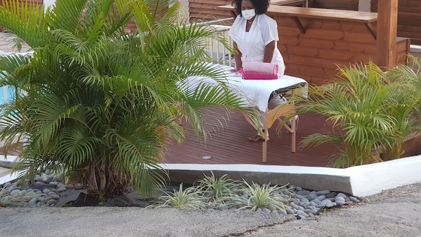 A wooden deck with a bench, surrounded by lush green plants and a white fence. - The Island Paradise (Baillif)