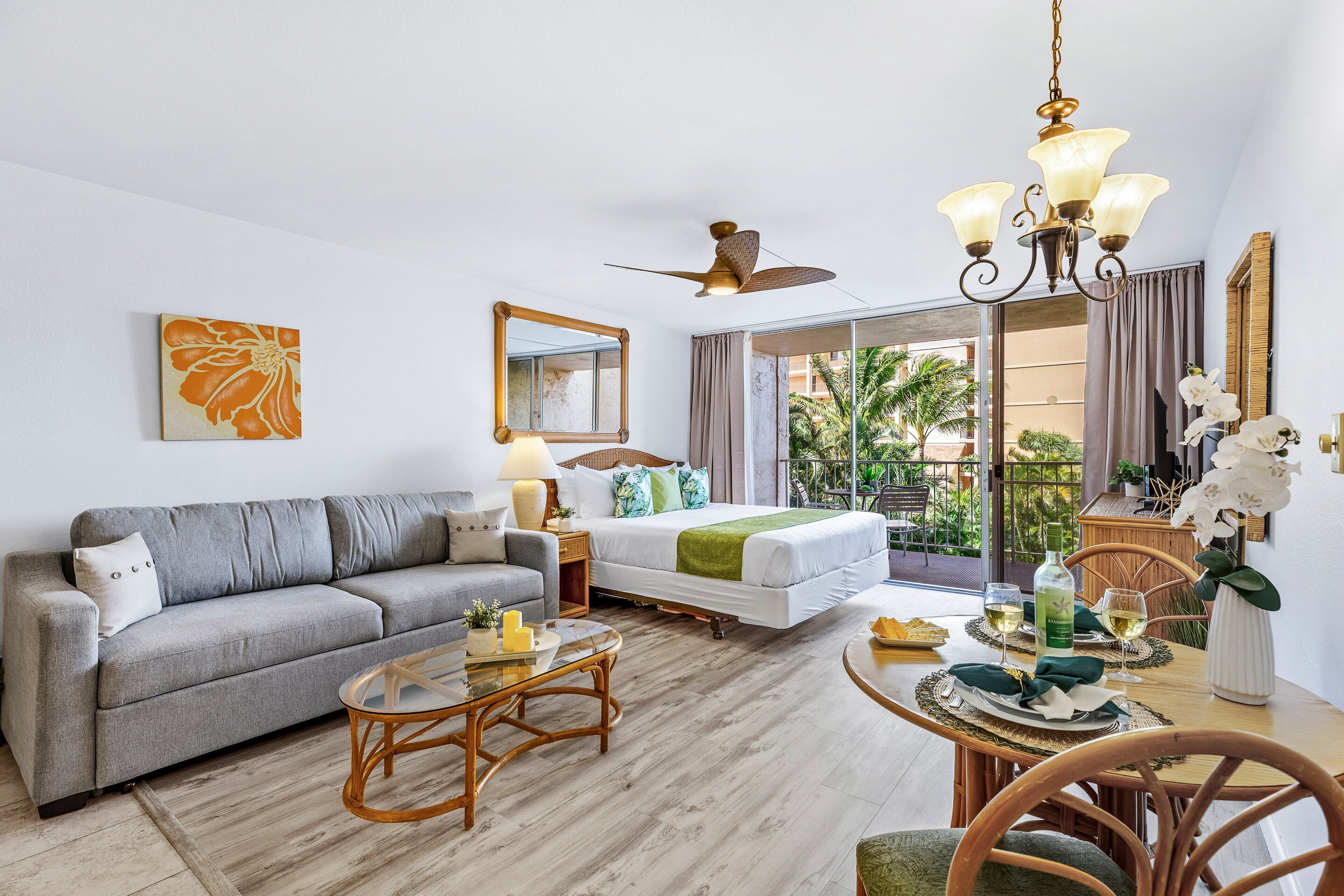 A modern hotel room with a sofa, a bed, a dining table, and a balcony with a view.