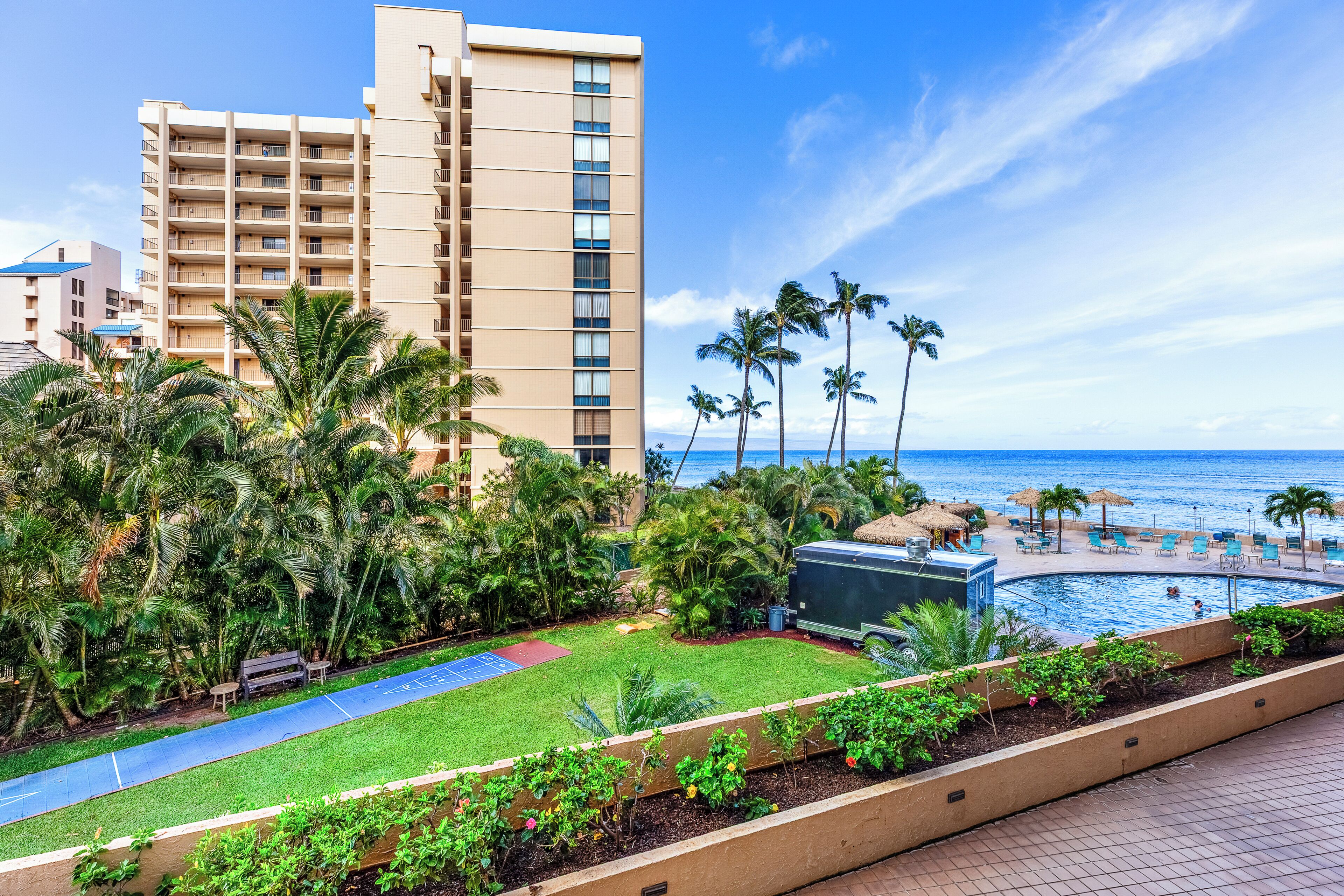 A hotel with a pool, palm trees, and a view of the ocean.