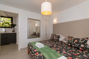 Quarto com cama, espelho, luminária pendente e vista para o exterior.
