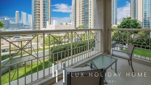 Ein Balkon mit Glastisch und Stühlen, mit Blick auf eine Skyline aus hohen Gebäuden und einem klaren Himmel.
