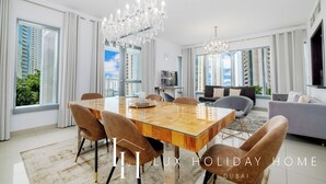 Ein modernes Wohnzimmer mit einem großen Esstisch aus Holz, bequemen Sitzgelegenheiten und einer Deckenleuchte.