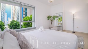 Ein modernes Hotelzimmer mit einem großen Bett, einer Chandelüster, einer Stehlampe und Blick auf die Stadt.