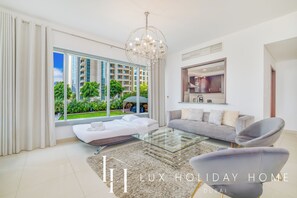 A modern living room with a glass coffee table, two sofas, and a chandelier. - LUX The Downtown Blvd Suite (Dubai)