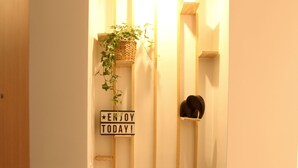 Een smalle gang met een houten bankje, een klein plankje met een plant erop, en een bordje met de tekst 'ENJOY TODAY!'