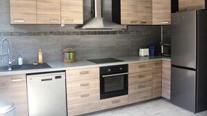 Een moderne keuken met houten kastjes, een roestvrijstalen koelkast, een vaatwasser en een magnetron.