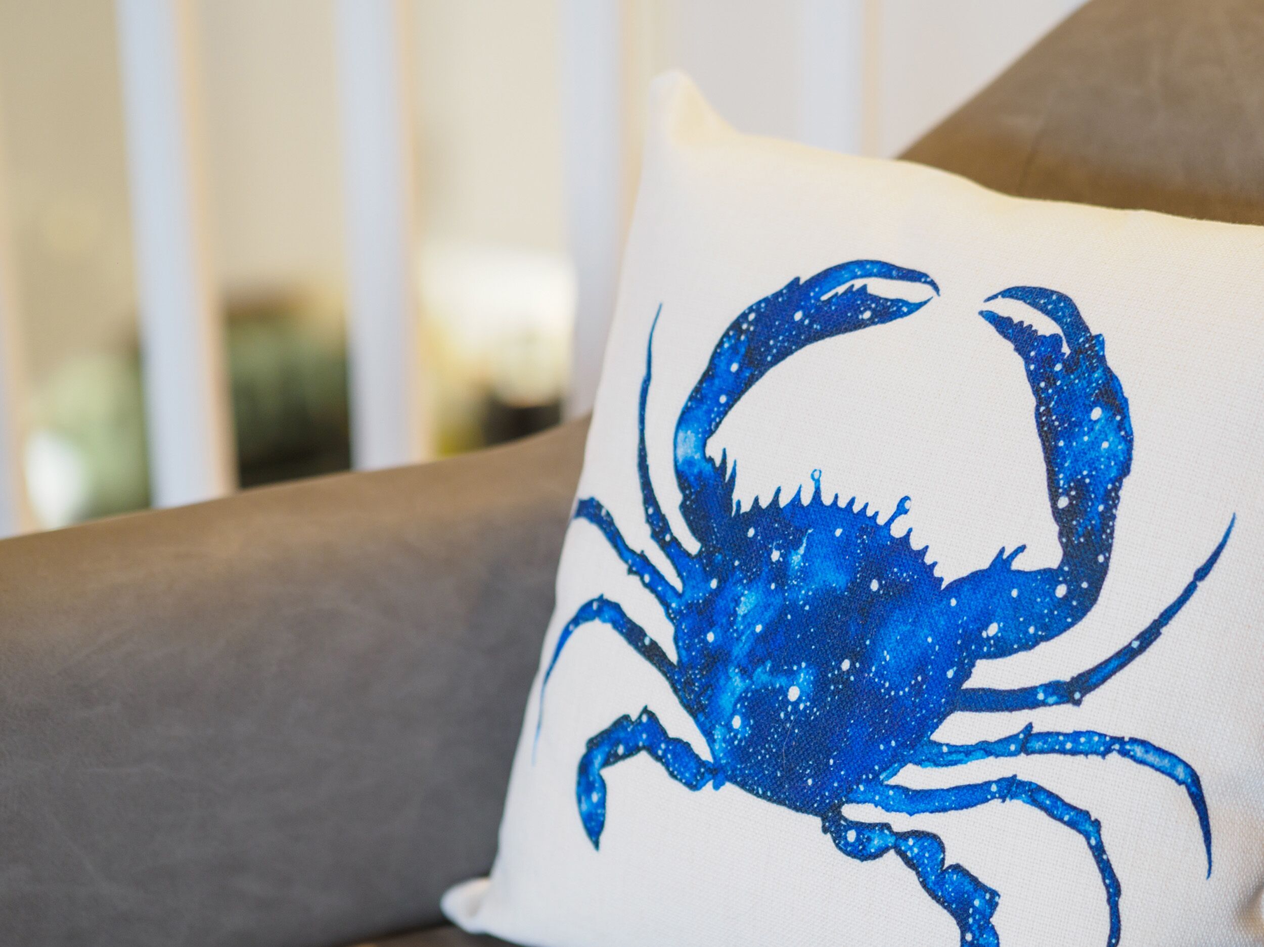 Ein Detailaufnahme eines weißen Kissens mit einem blauen Krabbenmotiv.