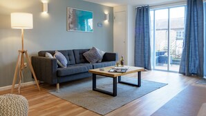 A modern living room with a sofa, coffee table, floor lamp, and a painting on the wall. - Coverack (Falmouth)
