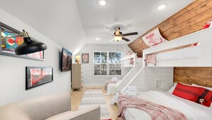 Un dormitorio moderno con camas literas, ventilador de techo y obras de arte en las paredes.