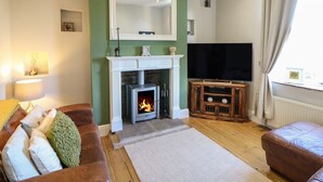 Una sala de estar con chimenea, televisión y sofá.