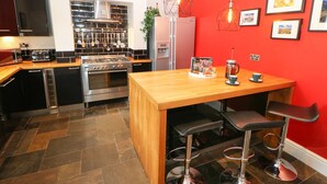 Una cocina moderna con una isla de madera, electrodomésticos de acero inoxidable y paredes rojas.