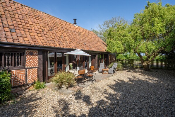A house with a tiled roof, outdoor seating area, and a gravel driveway.