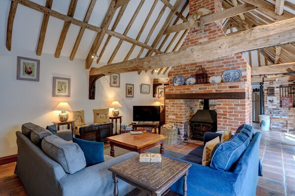 A cozy living room with a fireplace, wooden beams, and comfortable seating.