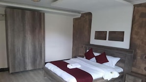 A bedroom with a wooden bed, white linens, and a red throw blanket. - Three Rivers Resort Maragua (Nairobi)