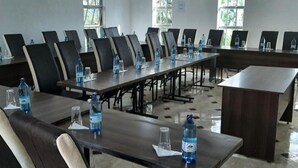 A conference room with multiple tables and chairs, water bottles on tables, and windows with natural light. - Three Rivers Resort Maragua (Nairobi)