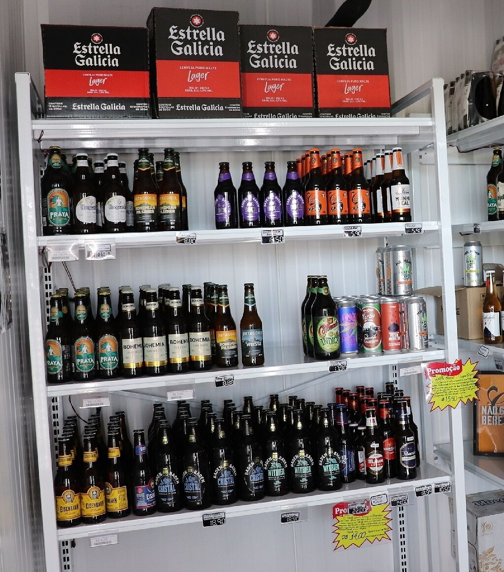 A refrigerated display of various beer brands and types, including Estrella Galicia and PRAYA, with price tags visible.
