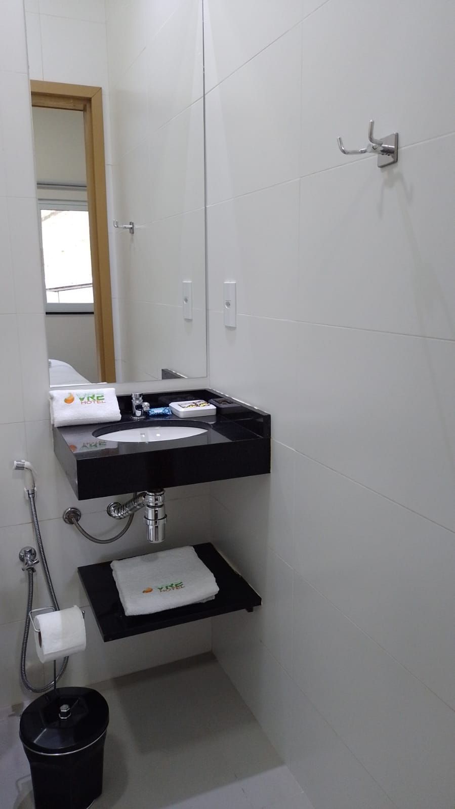 A bathroom with a white sink, mirror, and towel rack.