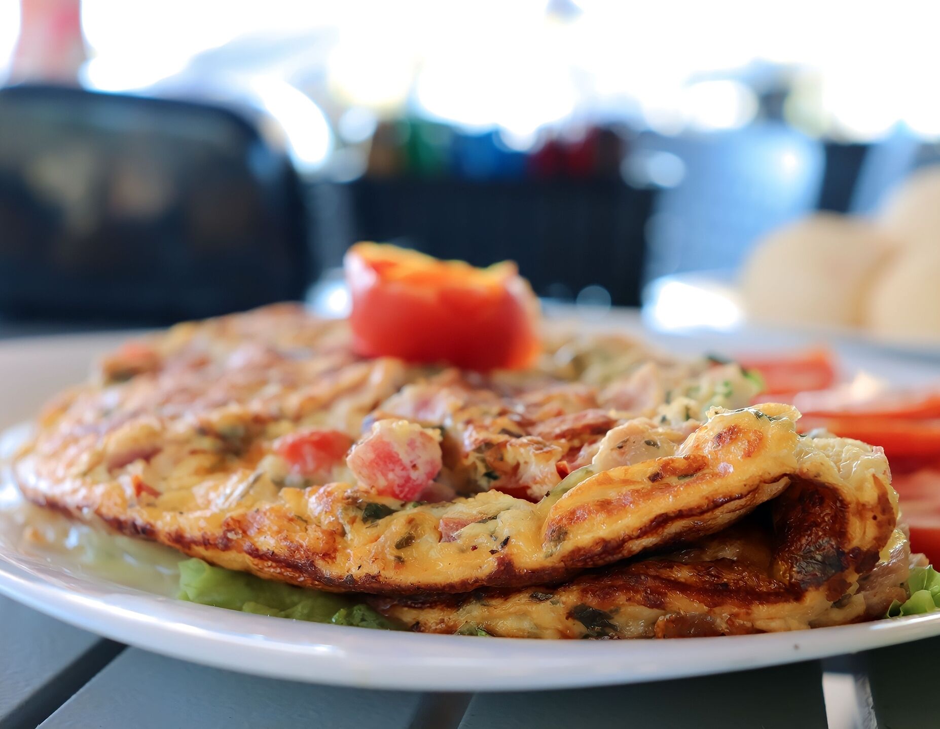 A plate of food with a slice of pizza and a piece of tomato on a white plate.