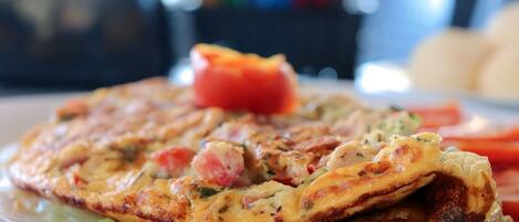 A plate of food with a slice of pizza and a piece of tomato on a white plate.