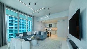 A modern living room with a sofa set, a coffee table, and a TV mounted on the wall. - Maison Privee - Sunrise Bay Tower 2 (Dubai)