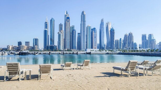 A beach with lounge chairs and a marina with boats. - Maison Privee - Sunrise Bay Tower 2 (Dubai)