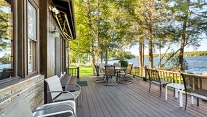 A wooden deck with outdoor seating, overlooking a lake. - 4 Bedroom Waterfront Home With Beatutiful Lake and Mountain Views (Moultonborough)
