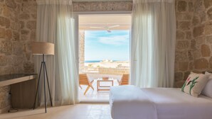 A bedroom with a bed, a desk, a lamp, and a view of the sea through a glass door. - Wadi Sabarah Lodge (Marsa Alam)