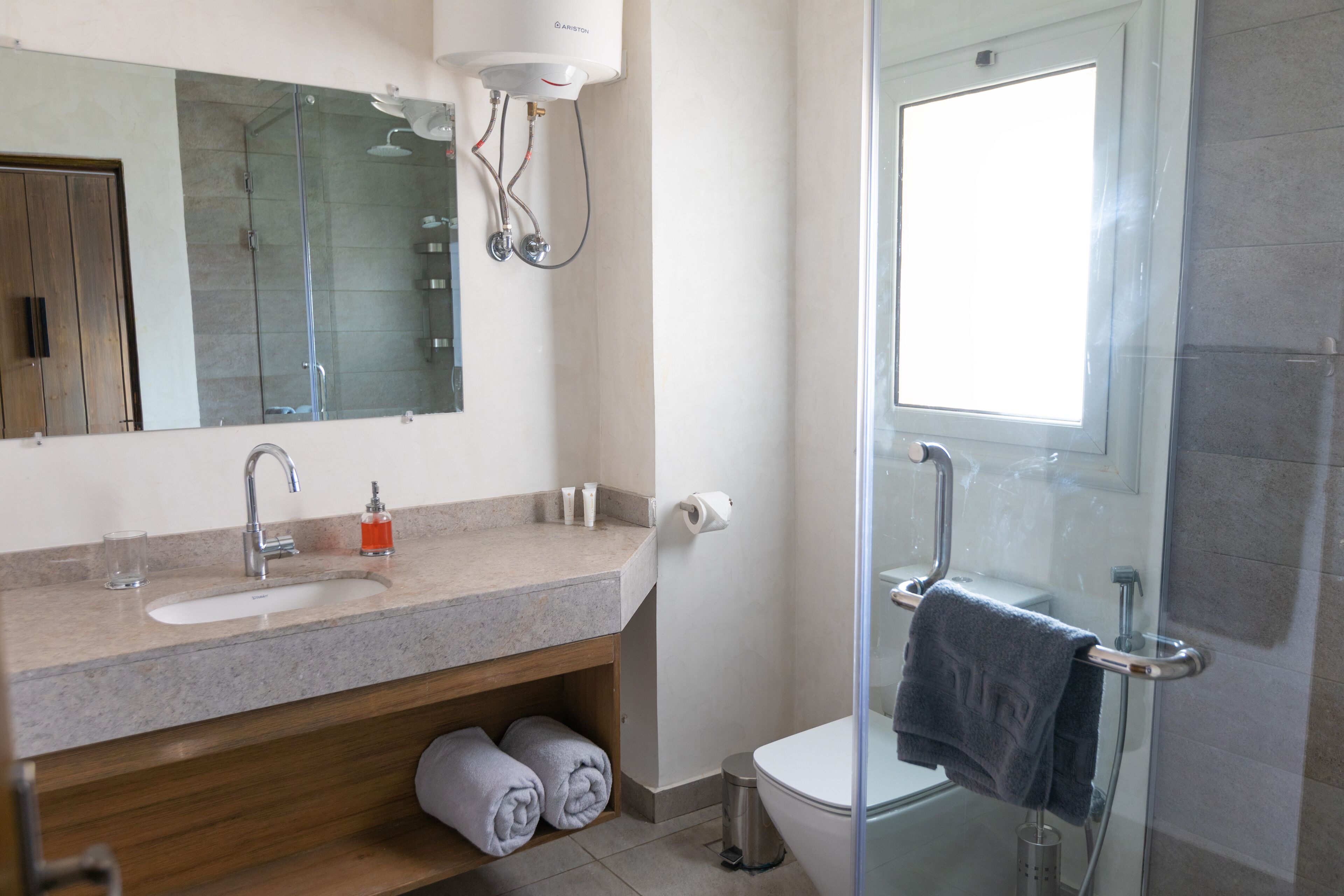 Un bagno moderno con lavandino, specchio, WC e cabina doccia in vetro.