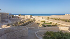 A coastal area with stone buildings, a beach, and a clear sky. - Wadi Sabarah Lodge (Marsa Alam)