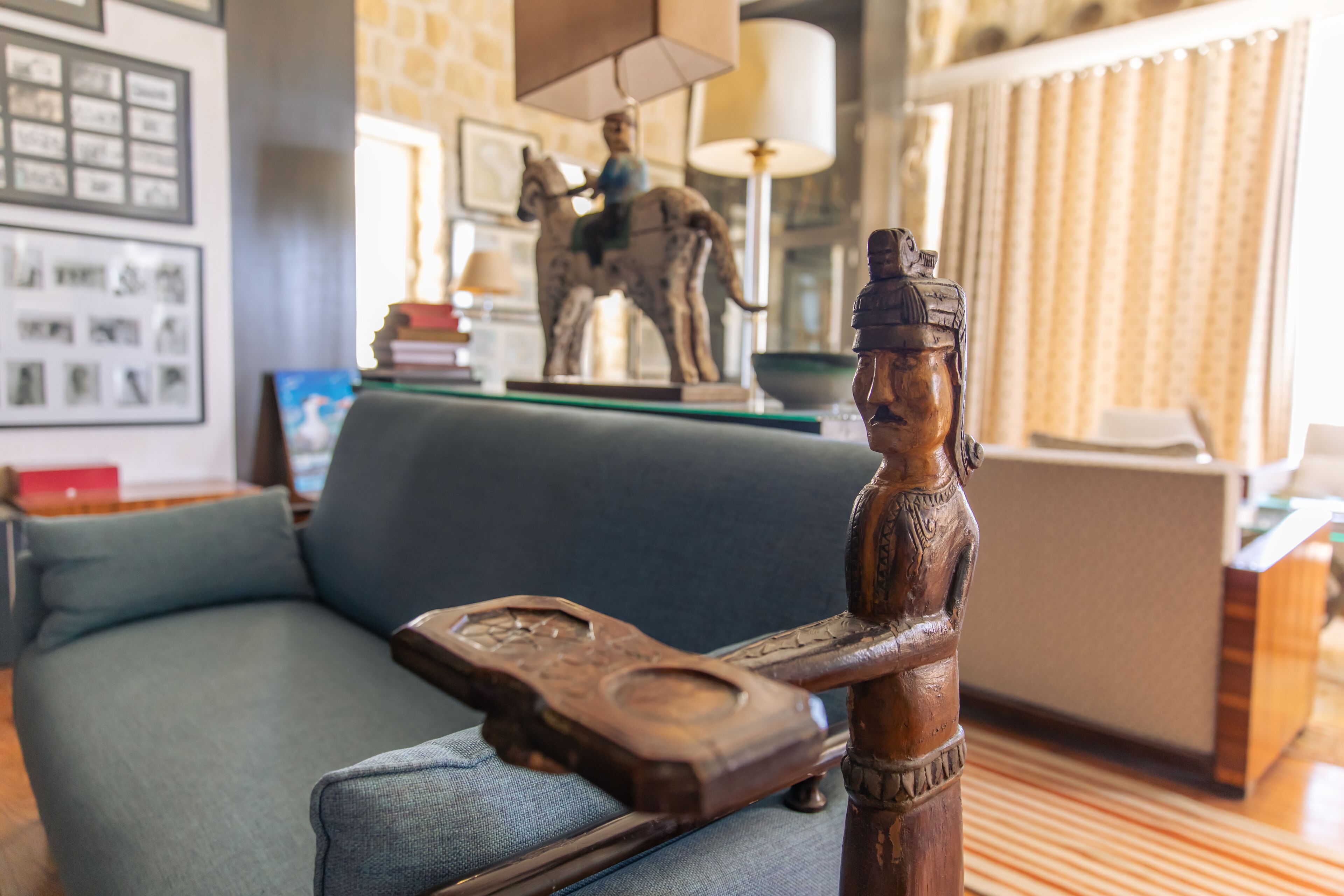 Une pièce comprenant un canapé, une sculpture en bois et une lampe.
