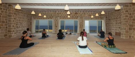 A yoga studio with stone walls, large windows, and wooden floors.
