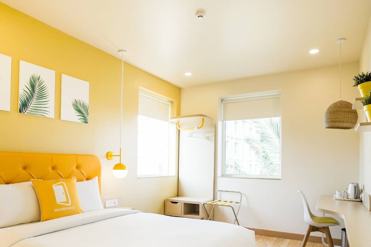 Habitación de hotel con una cama grande, un escritorio, una silla y una ventana.