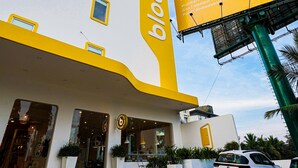 Un hôtel au design moderne, qui se distingue par son logo en forme de fleur stylisée et par un grand panneau publicitaire présentant différents établissements.