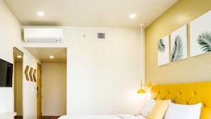 Une chambre d’hôtel équipée d’un lit, d’une table de chevet, d’un miroir et d’un téléviseur fixé au mur.