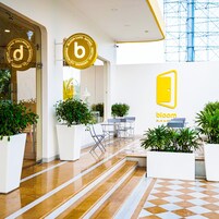 A modern interior with a checkered floor, potted plants, and a seating area with tables and chairs.