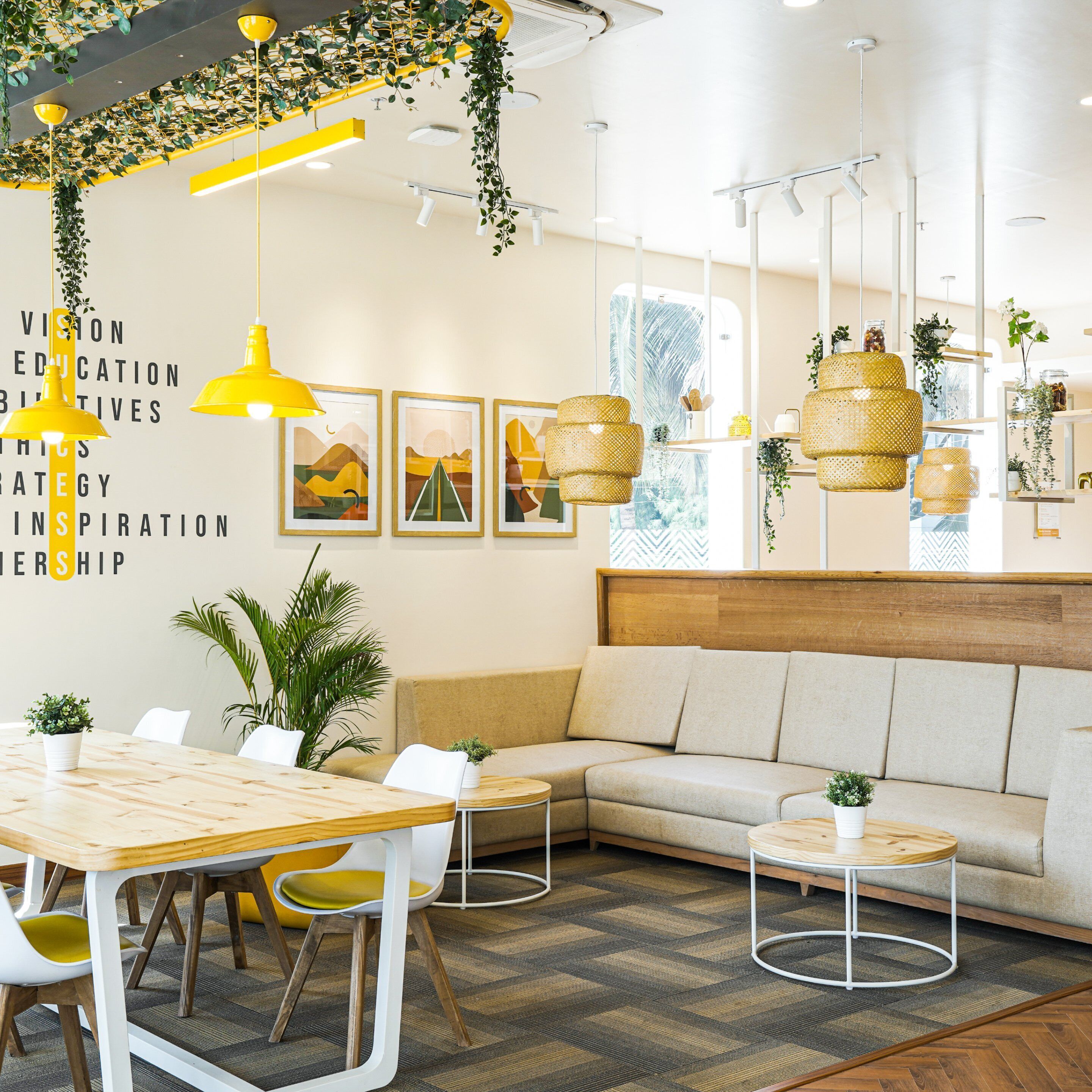 A modern interior with a wooden table, white chairs, a sofa, and hanging plants.