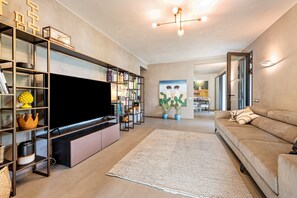Ein modernes Wohnzimmer mit Flachbildfernseher, Einbauschränken, einem großen Teppich und einer Couch.