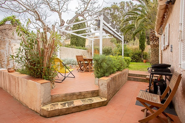 A patio with a pergola, outdoor seating, and a barbecue grill.